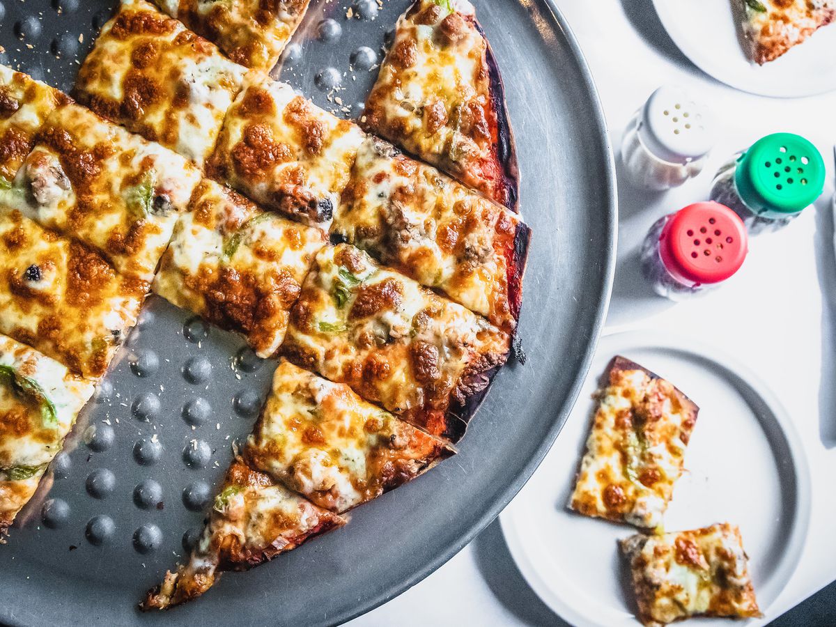 A Chicago tavern-style pizza with a few pieces missing.