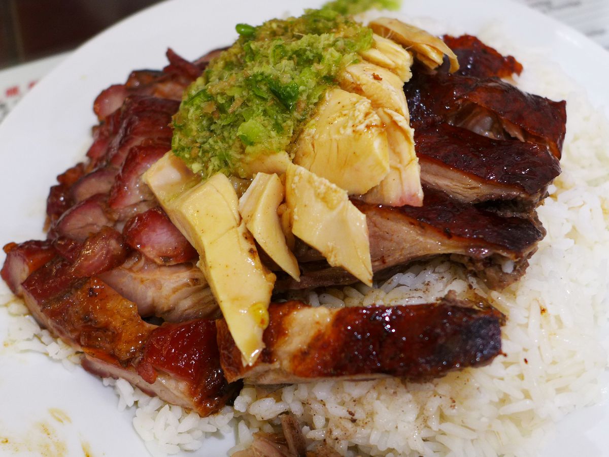 A heap of three barbecued meats with a drizzle of green sauce, served over rice.