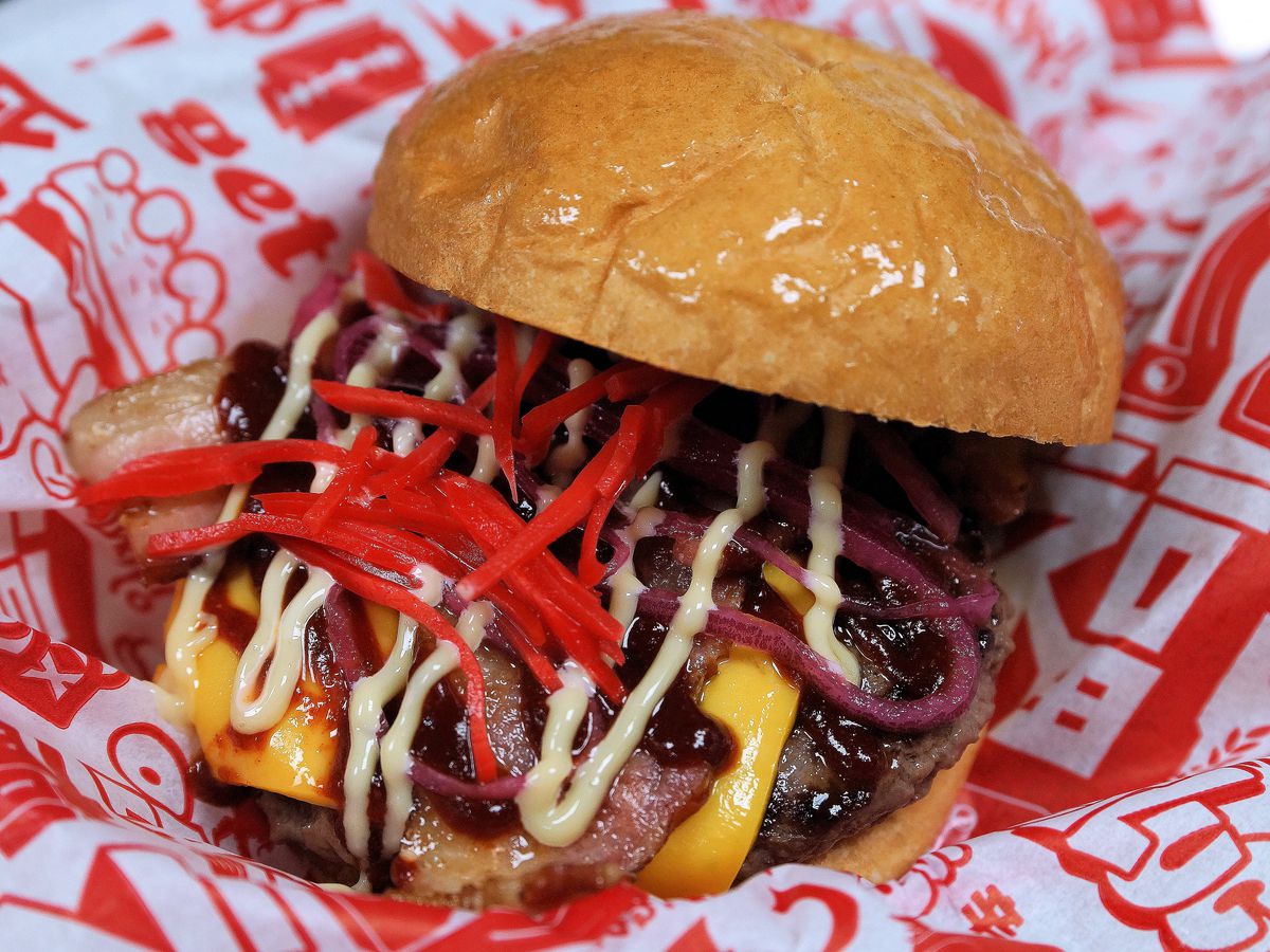 A heavily-sauced burger on a piece of colorful paper