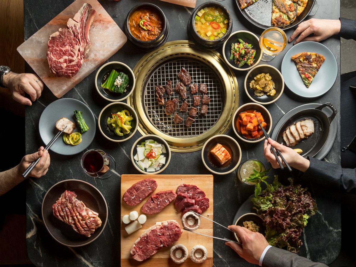 Get immersed in the captivating sight of banchan surrounding a sizzling Korean barbecue grill.
