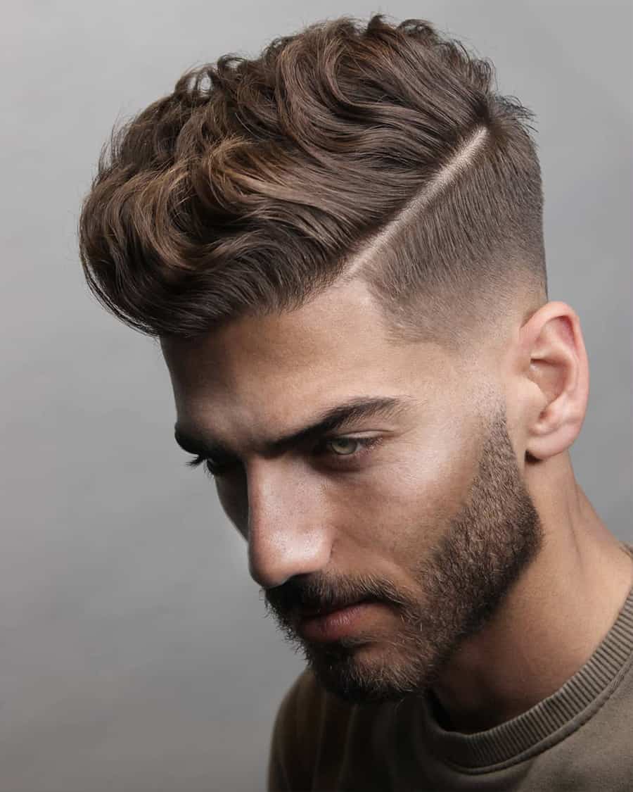 Men's mid-length wavy hair with a hard parting and low fade