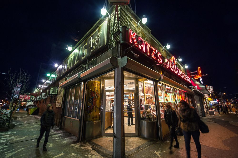 The iconic red neon letters spelling “Katz’s Delicatessen” on the exterior of the sprawling corner store at night.
