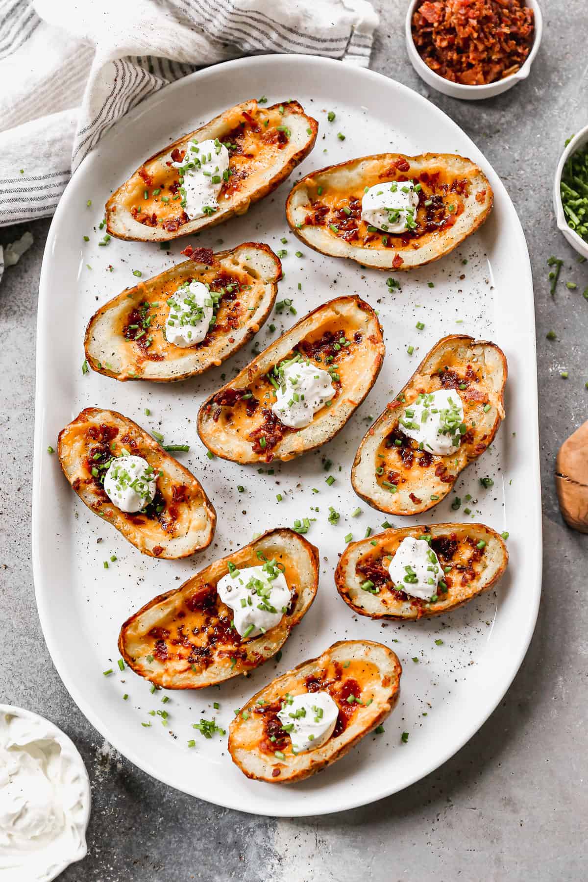 Easy potato skins with some of the potato scooped out and a pastry brush putting butter on it to go in the oven.